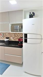 cocina blanca con nevera y microondas en Le Premier Residence, en Niterói
