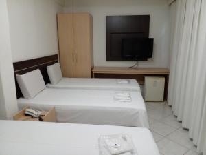 a hotel room with two beds and a flat screen tv at Hotel Minas Brasil in Montes Claros