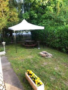 una mesa de picnic bajo un paraguas blanco en un patio en ZENITH APARTMAN, en Gárdony