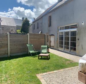 a yard with two chairs and a fence at Villa kahlo Omaha Beach in Colleville-sur-Mer