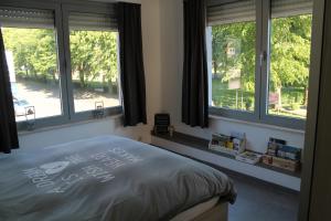 a bedroom with windows and a bed with writing on it at De Reünie - airconditioned duplex appartement & fietsgarage in Langemark