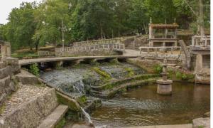 eine Brücke über einen Fluss in einem Park in der Unterkunft CAMBOTE Vivienda turìstica in Lugo