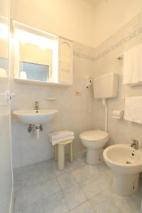 a white bathroom with a sink and a toilet at Hotel Savoia in Lido di Jesolo