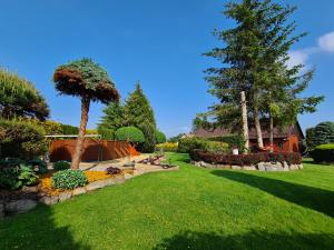 a garden with a lawn and trees and a house at Ostoja Relaksu Cieciorka in Kaliska