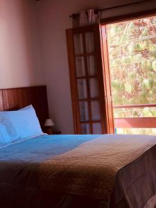 a bedroom with a bed and a large window at Chales Mãe e Filho in Monte Verde