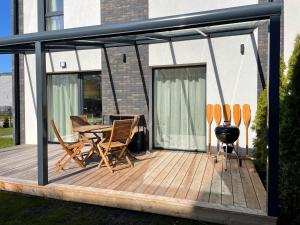 a deck with a grill and chairs on a house at Amber-Blue Palanga in Palanga