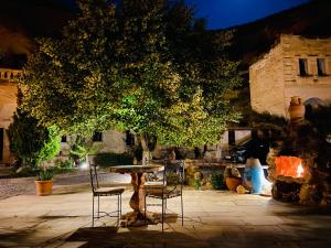 a table and chairs under a tree in a courtyard at The Village Cave Hotel in Göreme