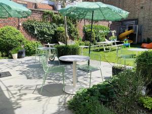 un patio con mesa, sillas y sombrilla en Lichtrijke loft bij restaurant Den Olifant, en Ypres