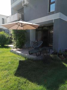 een patio met een parasol en een tafel en stoelen bij Untold 2024 - 3-room apartment with garden for 6-8 person, 2 private parking in Cluj-Napoca
