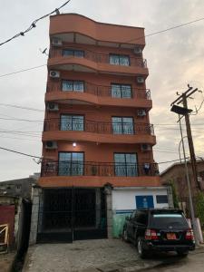 a tall building with a car parked in front of it at Appartement chic et moderne in Douala