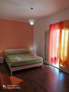 a bedroom with a green bed and a window at Il Peperoncino in San Vito lo Capo