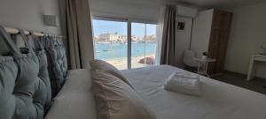 a bedroom with a bed with a view of the ocean at Eos Sea View Apartments in Siracusa