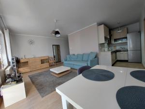 a living room with a blue couch and a kitchen at Apartament Ania in Świnoujście