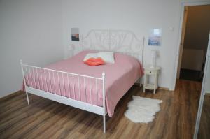 a bedroom with a pink bed and a wooden floor at Apartman Gulliver in the center, 10 meters from the sea with private parking in natural shade in Rabac