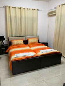 a large bed with orange sheets in a room at Joseph apartment in Bethlehem