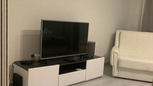 a flat screen tv on a white entertainment center next to a chair at Colors Apartment Sarajevo in Sarajevo