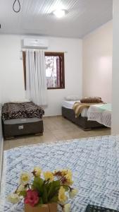 a room with two beds and a flower arrangement on a rug at Hotel Pousada Rolantchê in Rolante