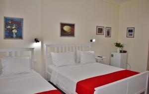 1 dormitorio con 2 camas blancas con manta roja en Kripis Studio en Pefkohori