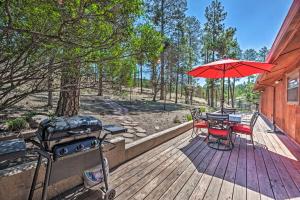 eine Holzterrasse mit einem Grill und einem Tisch mit einem Sonnenschirm in der Unterkunft Wooded Ruidoso Hideaway with Deck Ski, Hike and Golf! in Ruidoso