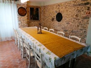 una mesa y sillas en una habitación con una pared de piedra en La Chouette, en Pieve di Teco