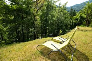 three lawn chairs sitting on a hill in a field at Cottages Kravanja in Trenta