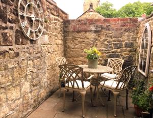 una mesa y sillas en un patio con una pared de piedra en Falstaff House, listed building, a delightful late-Georgian holiday cottage in a great location in central Alnwick, en Alnwick
