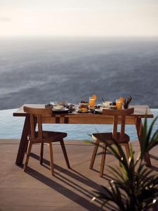 Etheria Luxury Villas & Suites في آغيوس نيكولاوس: طاولة خشبية مع طعام فوق الفناء
