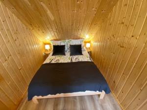 Ce lit se trouve dans un dortoir en bois doté de 2 lampes. dans l'établissement Lawendula domek nad Miedwiem, à Morzyczyn