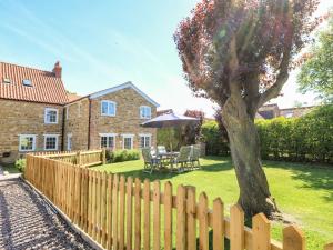 a wooden fence in front of a house with a tree at Paddock View Cottage in Grantham