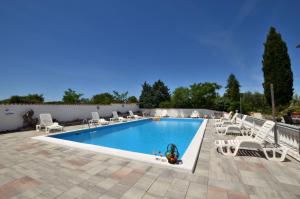 een zwembad met witte stoelen en een zwembad bij Rooms Aurora in Pula