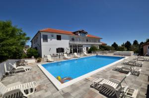 een zwembad met stoelen en een gebouw bij Rooms Aurora in Pula