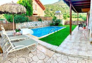 a backyard with a swimming pool with chairs and an umbrella at Villa Katerina in Stalida
