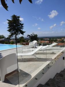 two white chairs sitting on a ledge next to a pool at Villa Vista in Sesimbra