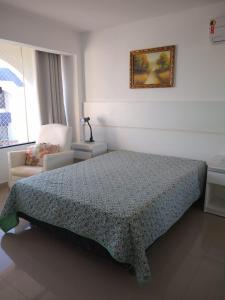 a bedroom with a bed and a chair at BEACH APARTMENT IN VILAS DO ATLANTICO in Lauro de Freitas
