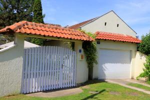 uma garagem branca com um portão branco em frente a uma casa em Šumski raj em Subotica