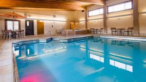 a large swimming pool in a building with tables and chairs at Best Western Sunset Inn in Cody