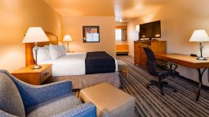 Pokój hotelowy z łóżkiem, biurkiem i krzesłami w obiekcie Best Western Sunset Inn w mieście Cody