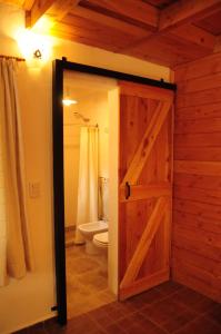 a bathroom with a wooden door and a toilet at La Aljaba in El Bolsón