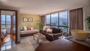 a living room with a couch and a large window at Alcazar de Oviedo by EE Hoteles in Medellín