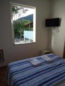 um quarto com uma cama de listras azuis e uma janela em Pousada Vó Irene em Itacuruçá