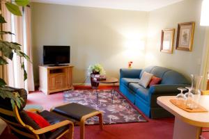 a living room with a blue couch and a tv at Summers Inn Ludington - Adults Only in Ludington