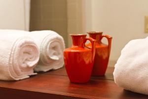 two red vases sitting on a table next to towels at Summers Inn Ludington - Adults Only in Ludington