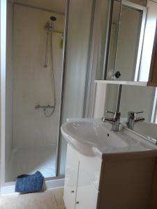 a white bathroom with a sink and a shower at Apartment De Paprente in Merkem