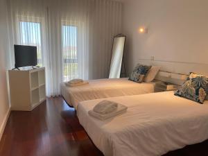 a room with two beds and a television in it at Beach Front with Rooftop in Vila do Conde