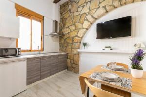 - une cuisine avec une table et un mur en pierre dans l'établissement apartamento loft a 50 metros de la playa y paseo maritimo, à El Campello