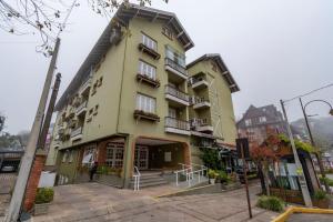 a yellow building with balconies on a street at Rosa Edifício Saint Moritz in Gramado