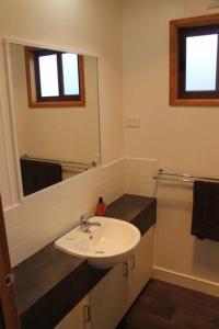 La salle de bains est pourvue d'un lavabo et d'un miroir. dans l'établissement OMARU FARM STAY, à Ventnor
