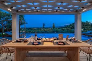 een grote houten tafel met wijnglazen op een patio bij Villa Plumeria in Tsilivi