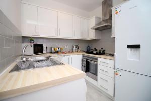 a white kitchen with a sink and a refrigerator at St Thomas Loft Views by Stay South Wales in Swansea