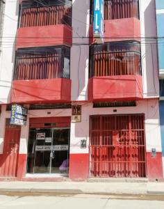 a red and white building with barred windows at Hostal Sumak'usi in Juliaca